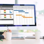 Business-professional-participates-in-a-focused-video-learning-session-demonstrating-growth-trends-on-whiteboard-while-actively-taking-notes-on-a-laptop